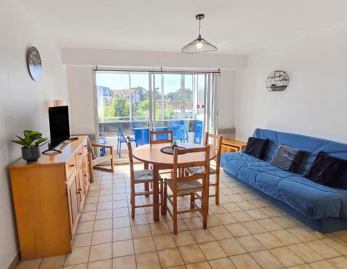 ein Wohnzimmer mit einem Tisch und einem blauen Sofa in der Unterkunft T2 Cosy à 800mètres de la mer in Saint-Jean-de-Monts