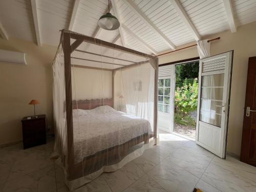 een slaapkamer met een hemelbed en een raam bij Kaz Raphitou in Bouillante