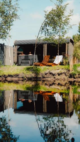 a house sitting next to a body of water at Natursee-Chalet, Angeln, Wellness, Spa, Ponyhof in Twist