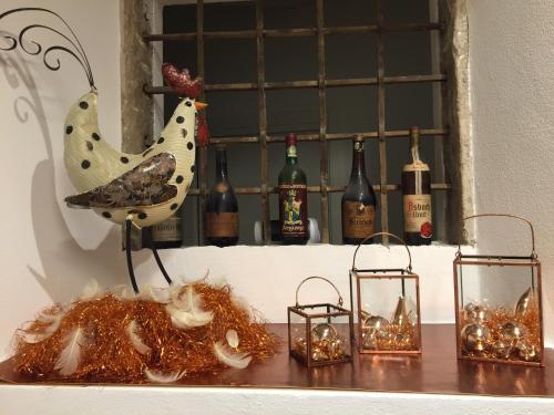 a statue of a chicken sitting on a table with wine bottles at Bed and Breakfast Casa Mosole in Malcesine