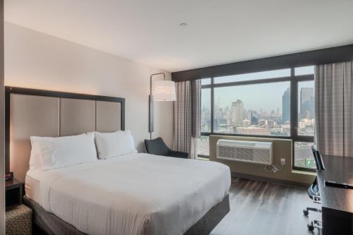 a hotel room with a bed and a large window at Holiday Inn Express Long Island City E - New York by IHG in Queens