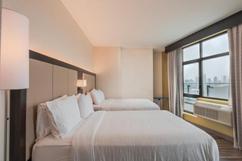two beds in a hotel room with a window at Holiday Inn Express Long Island City E - New York by IHG in Queens