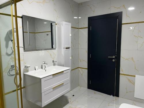 a bathroom with a white sink and a black door at Golden Hill Palace in Novi Pazar