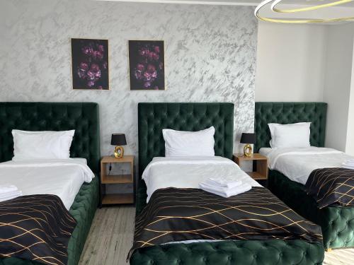 a bedroom with two beds with green tufted headboards at Golden Hill Palace in Novi Pazar