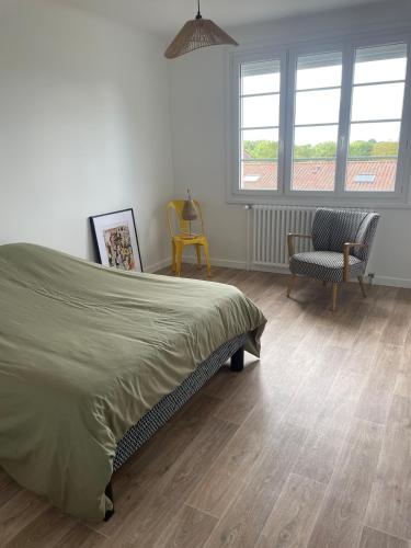 a bedroom with a bed and a chair and windows at Farmhouse in Montaigu-Vendée