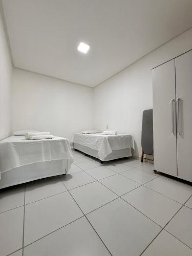 a white room with two beds and a cabinet at Edificio Artur Regis in Petrolina