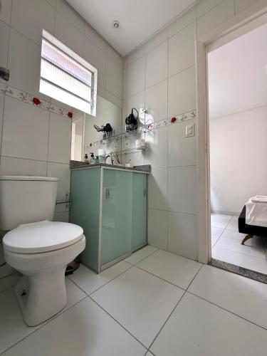 a white bathroom with a toilet and a sink at Edificio Artur Regis in Petrolina