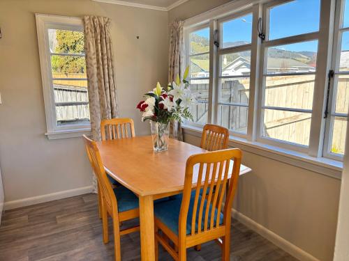 a dining room table with chairs and a vase of flowers at 3-Beds with Sunny Deck & Gardens in Nelson