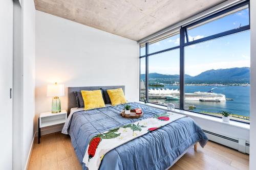 a bedroom with a bed with a view of the water at Stylish 2BR Loft in Historic Gastown with Mountain Views in Vancouver