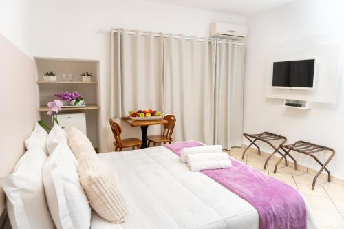 a bedroom with a white bed and a table with chairs at Hotel Palace 1 in Florianópolis