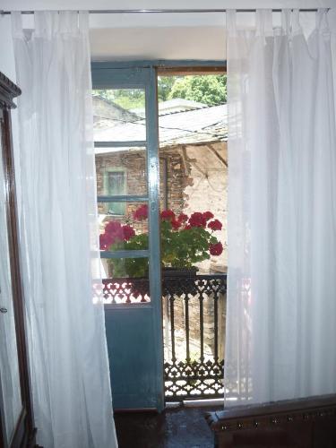 a door to a balcony with a window with a flower pot at Pensión Santa Rosa in Samos