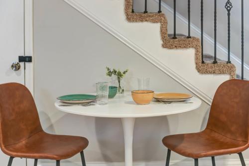 una mesa blanca con dos sillas y platos. en KING Bed FREE Parking English Basement, en Washington