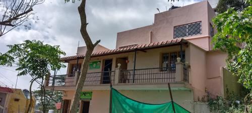 a pink house with a balcony on a street at Tn27callingkrishholiday in Yercaud