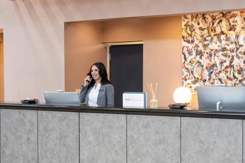 a woman talking on a cell phone at a reception desk at voco Kissimmee Orlando by IHG in Orlando