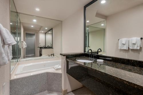 a bathroom with a bath tub and a sink and a bath tub at voco Kissimmee Orlando by IHG in Orlando