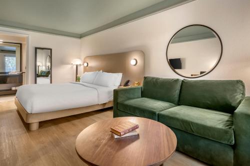 a hotel room with a bed and a green couch at voco Kissimmee Orlando by IHG in Orlando