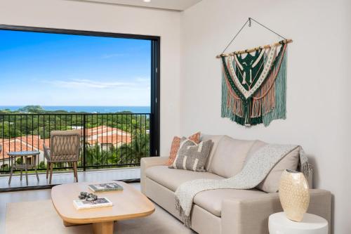 a living room with a couch and a large window at Costa Elena at Naumi, Ocean Views & Beach Club in Sardinal
