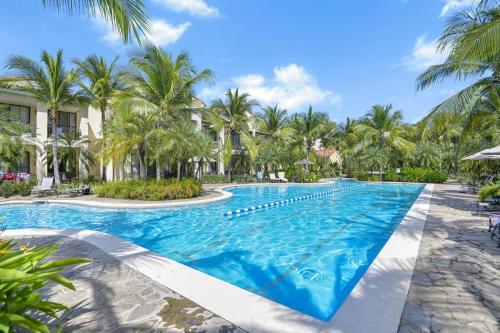 a pool at a resort with palm trees at Mar y Selva at Naumi, Ocean Views & Beach Club in Sardinal