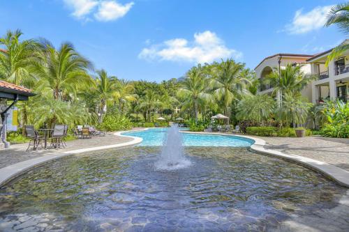 a fountain in the middle of a pool with palm trees at Mar y Selva at Naumi, Ocean Views & Beach Club in Sardinal