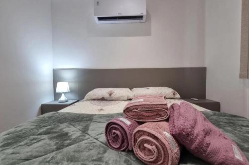 a bed with two rolls of pink blankets on it at Studio Moderno no Ingá com Vista in Niterói