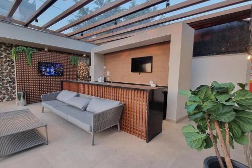 a patio with a couch and a bar with a tv at Studio Moderno no Ingá com Vista in Niterói