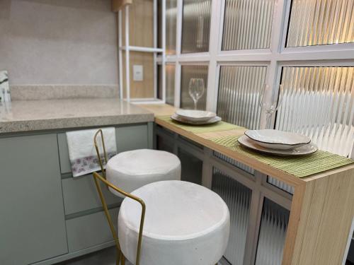 a kitchen with two stools and a counter with dishes on it at Apartamentos Exclusivos no Edifício City House in Barreiras
