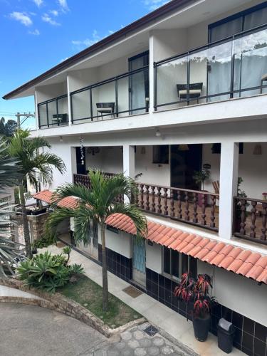 an apartment building with a balcony and palm trees at Pousada dos Sonhos - MP in Miguel Pereira