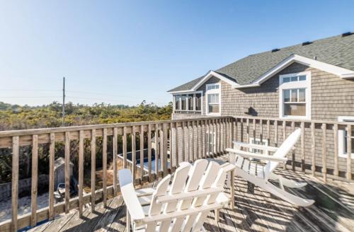 a deck with two white chairs and a house at Funtiki in Whalebone