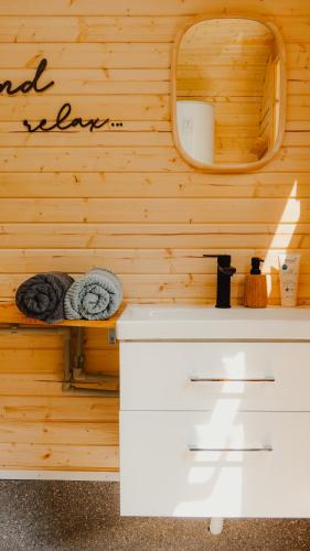 a bathroom with a sink and a mirror on a wooden wall at Schlaffass Natursee-Chalet mit Sanitärfass,Hot Tub,Sauna,Jacuzzi,angeln in Twist