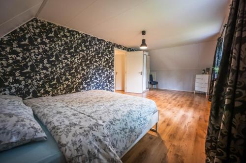a bedroom with a bed with a floral patterned wall at Luxe boshuis in hartje Drenthe in Spier