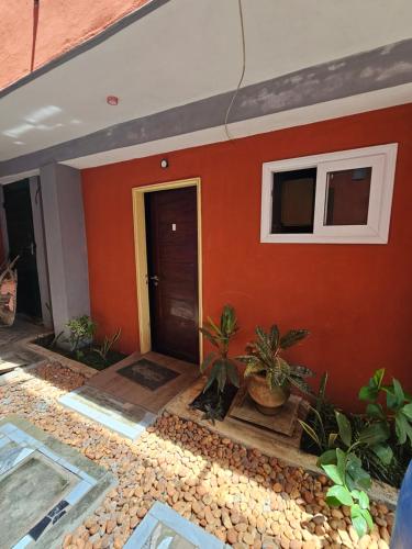 a house with an orange wall and a door at Home RÉSIDENCE OUIDAH in Ouidah