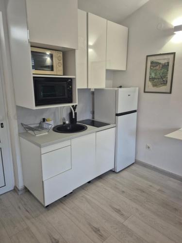 a kitchen with white cabinets and a microwave and refrigerator at Vidučić Apartments in Dragove