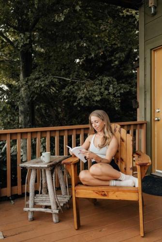 a woman sitting on a bench on a deck at Hoot Owl with a private hot tub in Bryant