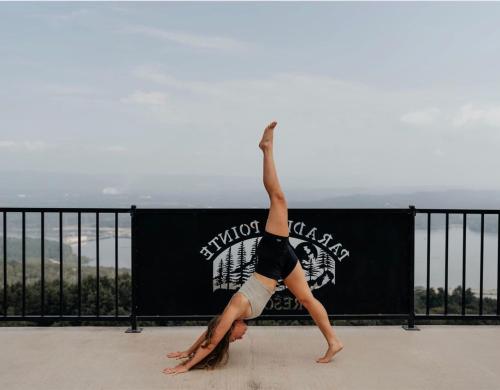 a woman doing a handstand on top of a balcony at Hoot Owl with a private hot tub in Bryant