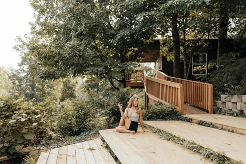 a woman sitting on the steps of a house at Fish Tales Cabin with a private hot tub in Bryant
