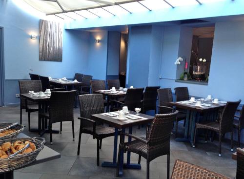 a dining room with tables and chairs in a restaurant at Hôtel de Flore in Saint-Raphaël