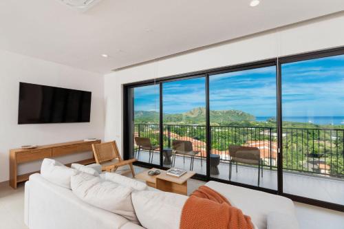 a living room with a white couch and a large window at Sol Pacífico at Naumi, Ocean Views & Beach Club in Sardinal