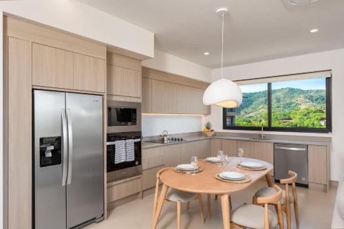 a kitchen with a table with chairs and a refrigerator at Sol Pacífico at Naumi, Ocean Views & Beach Club in Sardinal