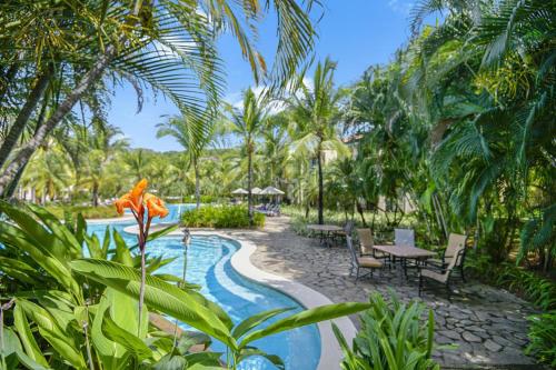 a resort with a pool and a table and chairs at Sol Pacífico at Naumi, Ocean Views & Beach Club in Sardinal
