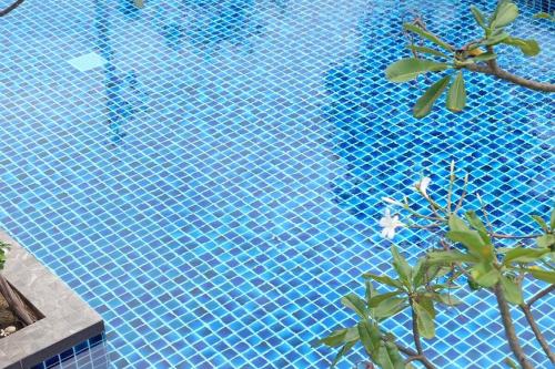 a blue swimming pool with a palm tree in it at Parsons Place in Chiang Mai! in Chiang Mai