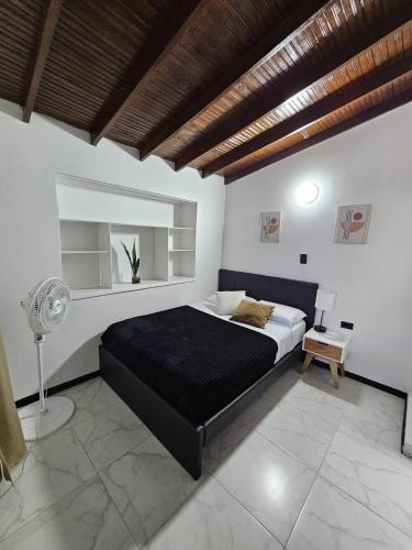 a bedroom with a black bed and a fan at Casa luz in Medellín