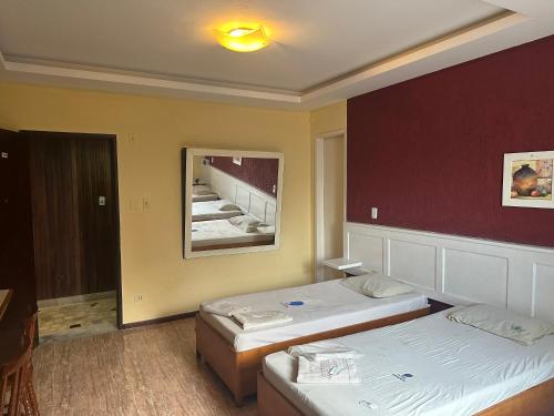 a hotel room with two beds and a mirror at Hotel Arsenal in São Gonçalo