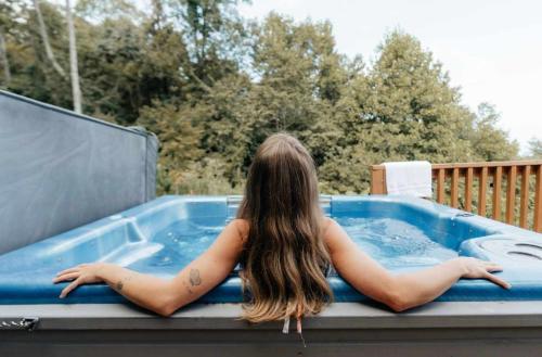 a girl is sitting in a hot tub at critter corner at Grant Summit Cabins in Bryant