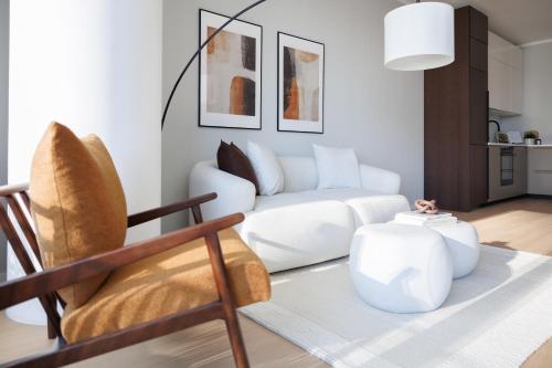 a living room with a white couch and a chair at Skyline Suite - Danube-View Balcony & Pool in Vienna