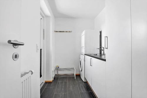 a white kitchen with a sink and a refrigerator at 0274-Romo-Nordre-Havnevej-42 in Havneby