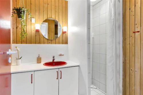 Un baño con un lavabo rojo y un espejo. en 0291-Romo-Vestergade-3-Ap-65, en Havneby