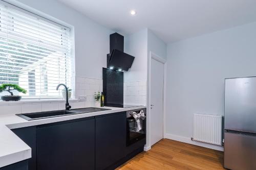 a kitchen with a sink and a refrigerator at 3BR House By Eason Stays Short Term Rental Wythenshawe Near Manchester Airport with Free Parking in Wythenshawe