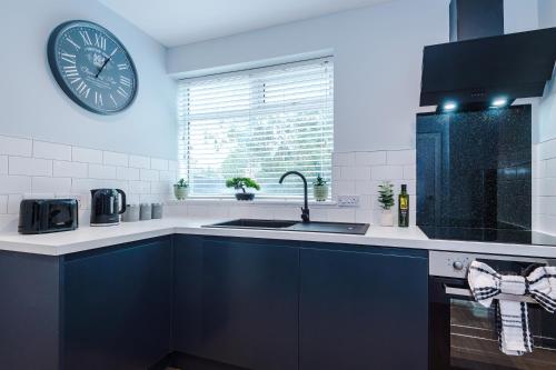 a kitchen with a sink and a clock on the wall at 3BR House By Eason Stays Short Term Rental Wythenshawe Near Manchester Airport with Free Parking in Wythenshawe