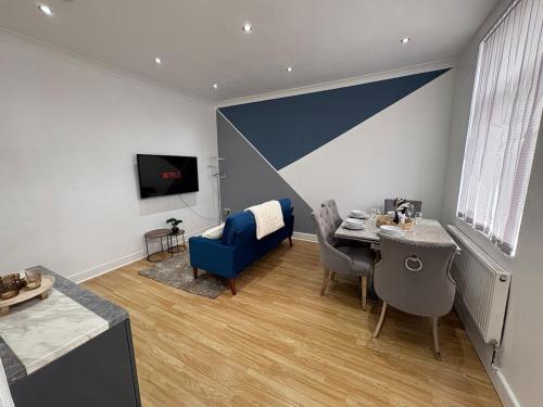 a living room with a table and a blue chair at Cliffton House, Sleeps 5, Parking,Netflix, WiFi, Only 6 min to City in Killingbeck
