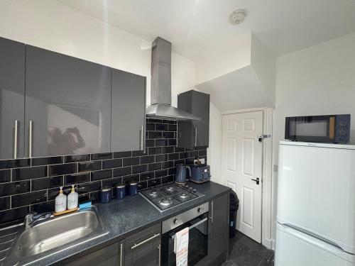 a kitchen with a sink and a stove and a refrigerator at Cliffton House, Sleeps 5, Parking,Netflix, WiFi, Only 6 min to City in Killingbeck
